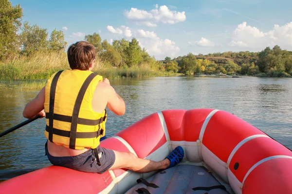 Rafting csapat, nyári extrém vízi sportok. Egy férfi egy sárga mentőmellényt egy evezős lebeg egy felfújható csónak a folyón. Gyönyörű adrenalin út a folyón lefelé. Vissza a nézetet. Pov — Stock Fotó