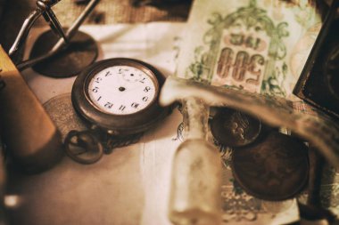 Masadaki farklı antika eşyalar: eski cep saatleri, banknotlar ve Rus İmparatorluğu sikkeleri, bir kasadaki gözlükler, gümüş eşyalar. Antika koleksiyonundan vintage arka plan. Seçili odak
