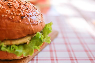 Susamlı vejetaryen burger, suni et, masa örtüsünde yeşil marul. Seçili odak