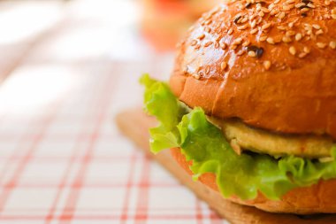 Susamlı vejetaryen burger, suni et, masa örtüsünde yeşil marul. Seçili odak 