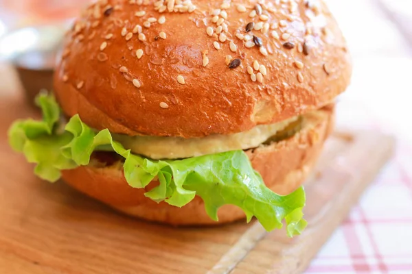 Close-up vegetarian burger with sesame seeds, artificial meat, green lettuce on the tablecloth.  Selected focus