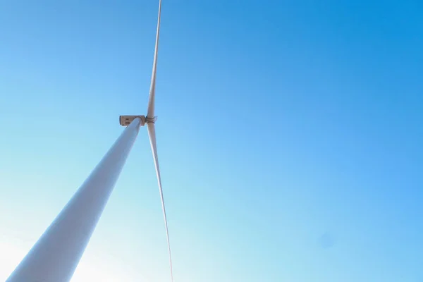 Mirando hacia arriba a un gran aerogenerador y un cielo azul. Fuente de energía alternativa, producción y generación de energía. Ecología y concepto de libertad — Foto de Stock