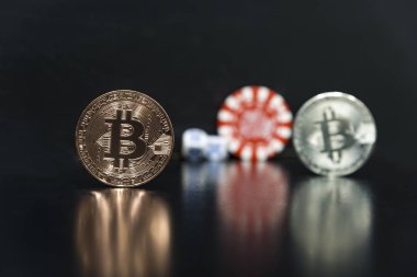 Bitcoin, casino fişlerini küpler. Oyun küpleri ile siyah bir arka plan üzerinde Bitcoins.