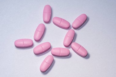 Beyaz kağıda pembe haplar. Beyaz arka planda bir grup pembe ilaç.