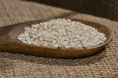 Ahşap kaşıklı inci arpa yüzey manzarasını kapat, inci arpa