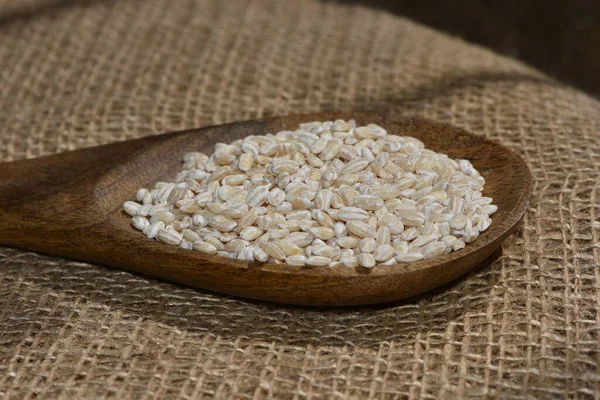 pearl barley with wooden spoon close up surface top view background, pearl barley