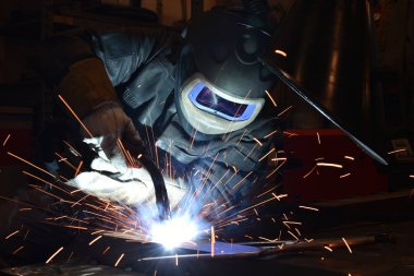 Kaynakçı metal kaynaklıyor, fabrikada teknik çelik endüstrisi kaynakçısı kuruyor.,