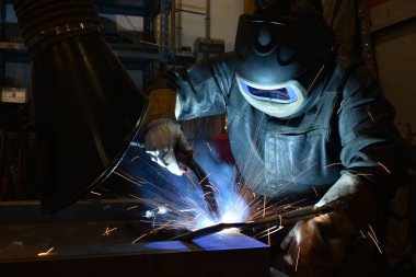 Kaynakçı metal kaynaklıyor, fabrikada teknik çelik endüstrisi kaynakçısı kuruyor.,