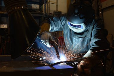 Kaynakçı metal kaynaklıyor, fabrikada teknik çelik endüstrisi kaynakçısı kuruyor.,