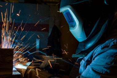 Kaynakçı metal kaynaklıyor, fabrikada teknik çelik endüstrisi kaynakçısı kuruyor.,
