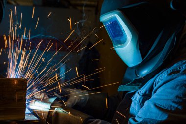 Kaynakçı metal kaynaklıyor, fabrikada teknik çelik endüstrisi kaynakçısı kuruyor.,