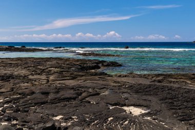 Puuhonua o Honaunau tarihi Parkı, Big Island, Hawaii mavi Pasifik Okyanusu görünümü. Defne kristal mavi-yeşil su; arka planda kıyı şeridi, volkanik kaya ve kum ön planda.