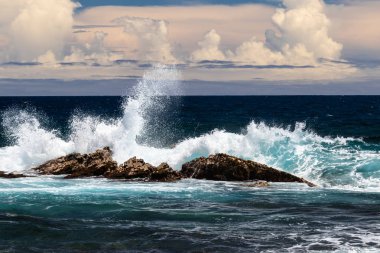 Bir volkanik çökmesini dalga offshore siyah kum Beach (Punaluu), Hawaii büyük ada rock. Beyaz deniz sprey, dalga bir yana havada; Pasifik Okyanusu ve bulutların arka planda olduğu.