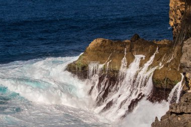 Endonezya 'nın Nusa Pendia adası, Kırık Sahildeki uçurumdan aşağı akan su. Ön planda köpük var. Arka planda derin mavi Pasifik okyanusu. 