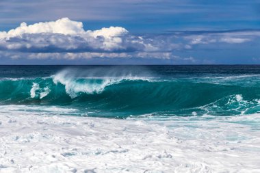 Hawaii 'nin Büyük Adası' nın batı Kona sahilinde dalga kırılması. Ön planda köpük ve sprey. Pasifik Okyanusu, gökyüzü ötesinde bulutlar. 