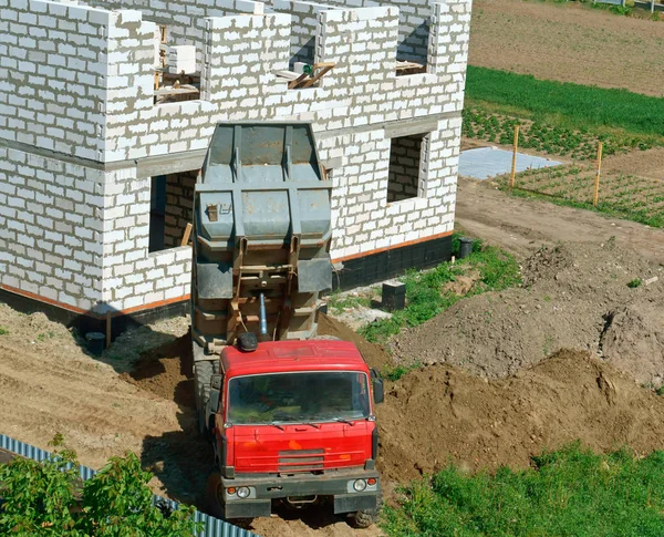 建設中の家の近くのダンプ トラック トラック 白いレンガの家の建物をダンプ トラックがに砂にもたらした — ストック写真