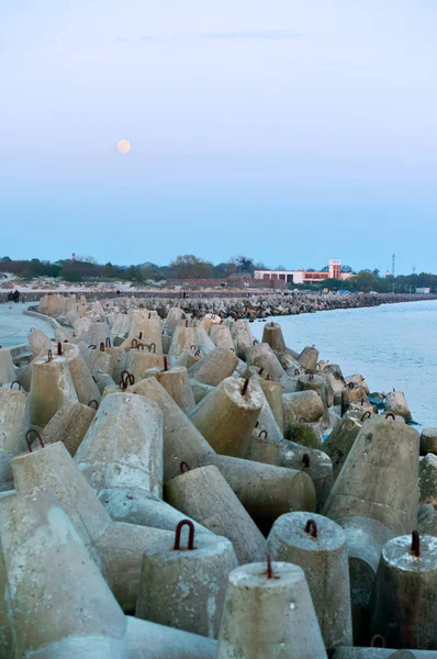 concrete breakwaters protecting the sea shore, pier sea and coastal fortifications, full moon and sea pier