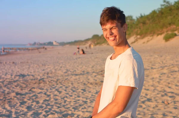 a nice young man is happy on the beach, a young man admires on the beach, the boy is very happy sea rest