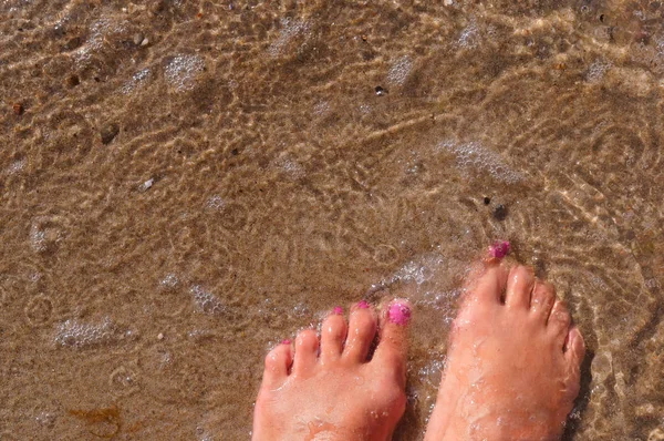 feet in water, female feet in the sand sea