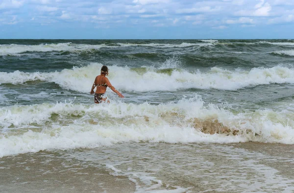girl bathes in the sea waves, swim during a storm at sea