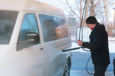 bir adam beyaz bir minibüs yıkar, bir adam bir van araba yıkamacıda kışın yıkar