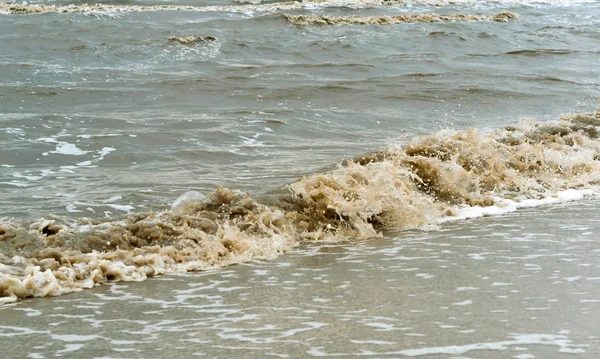 sea pollution, dirty yellow waves of the sea, the water is cloudy