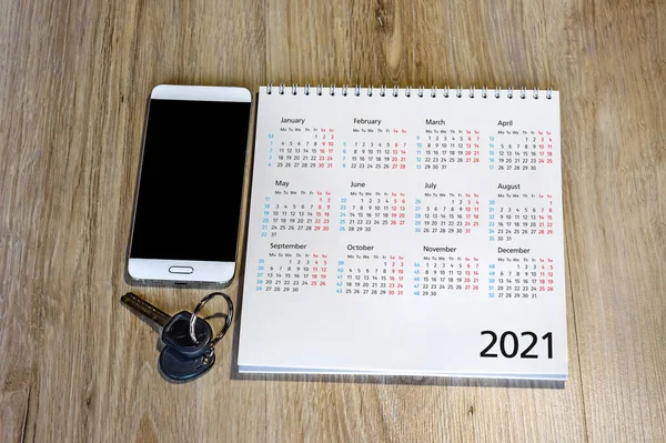 calendar for 2021 and keys on the table, white smartphone and calendar for 2021 (January, February, may, December)