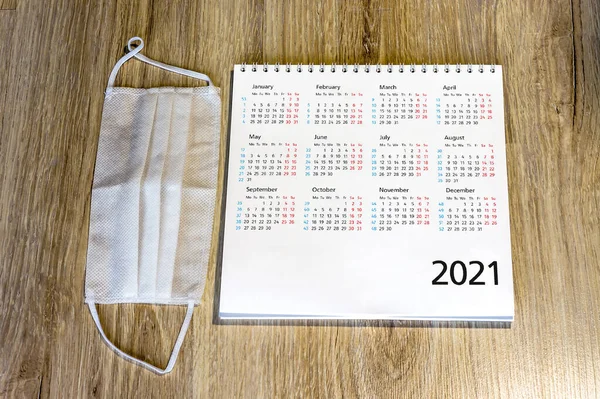 white medical mask and calendar for 2021, medical mask and passport on the table (January, February, May, December)