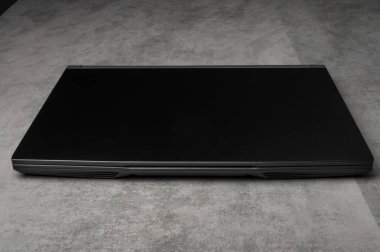 : Gri arka planda modern siyah bir dizüstü bilgisayarın stüdyo fotoğrafı. Teknoloji, iş, bilişim, yenilik ve taşınabilir bilgisayar kavramları için uygundur..