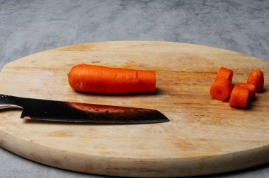 Taze turuncu havuç dilimlenmiş tahta kesim tahtasıyla bıçaklanmış, yemek pişirme ve sağlıklı yemek hazırlama sembolü.