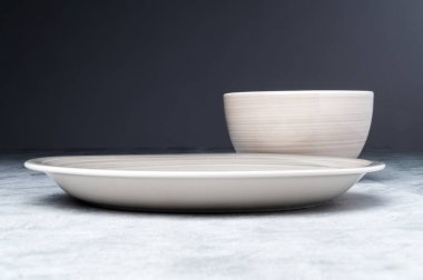 Dokulu bir yüzeyde minimalist seramik kase ve tabak..