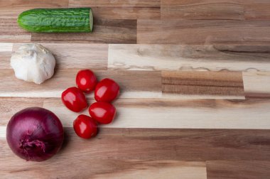 Çizgili ahşap kesme tahtasına yerleştirilmiş çeşitli taze sebzelerin tepeden tırnağa görüntüsü. Tarifler, yemek planlaması, yemek blogları ve fotokopi alanı olan yemek tasarımı için temiz mutfak hazırlık geçmişi.