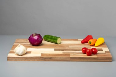 Sarımsak, soğan, salatalık, dolmalık biber ve domatesli ahşap kesim tahtası..