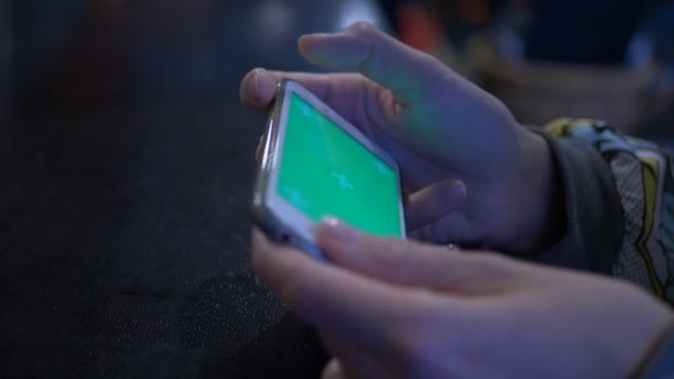 Hermosa chica sosteniendo un teléfono inteligente en las manos de una pantalla verde pantalla verde, mano del hombre sosteniendo teléfono inteligente móvil con croma pantalla verde clave sobre fondo blanco. Smartphone de juegos en la cafetería . — Vídeos de Stock