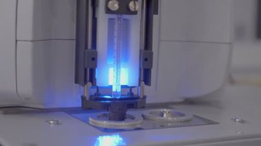 Gizli biyolojik silahlar. İğne ultraviyole radyasyondan örnek alıyor. Tıbbi laboratuvarda yakın çekim, robot bir iğne ile sıvı bir kavanoz deler ve bir tüp içine döker