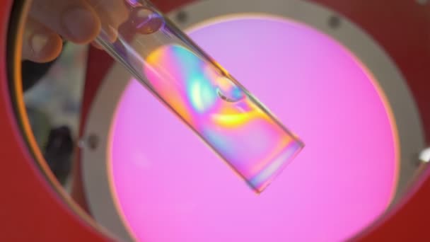 Vetro temperato arcobaleno. Uno scienziato sta considerando un nuovo campione di vetro. Esperimento su vetro. Proprietà del vetro. Rifrazione della luce. Prisma. Produzione di fiaschette mediche — Video Stock