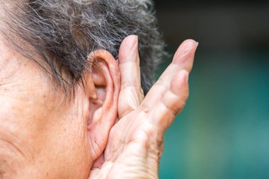 Üst düzey kadın sol kulak için elini tutarak yakın dinleyin için çalışıyor