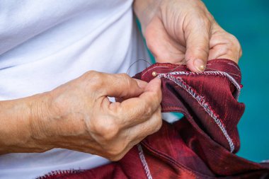 Kadın kıdemli dikiş kırmızı ipek bluz el ile yüzme havuzu arka plan, terzi bir işlem için yakın kadar