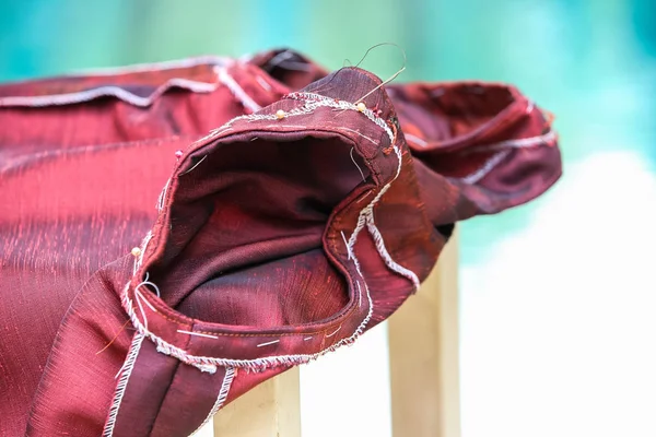 Red silk blouse put down on white chair at swimming pool background , About tailor process, Close up