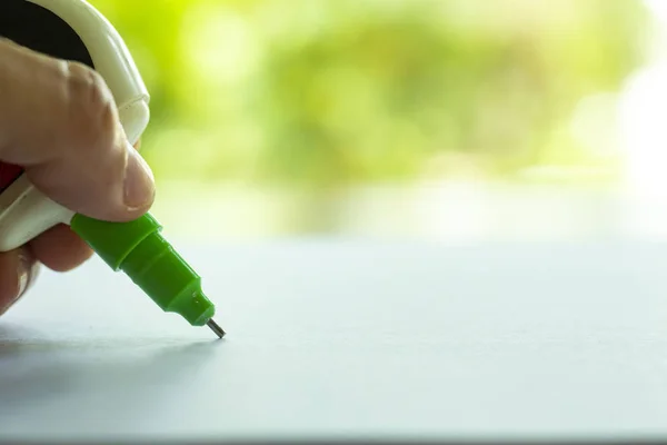 Mulher segurando verde Liquid Correction Writing Pen ou papel líquido para erros de escrita de mão correta no papel branco no jardim verde bokeh Fundo, Close up & Macro shot, Foco seletivo, Conceito de papelaria de escritório — Fotografia de Stock