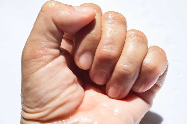 Ženská ruka mokré pěsti na bílém akrylové pozadí, zavřít & makro, selektivní zaměření, část kůže v asijském těle, relaxační koupel, koncepce zdravotní péče — Stock fotografie