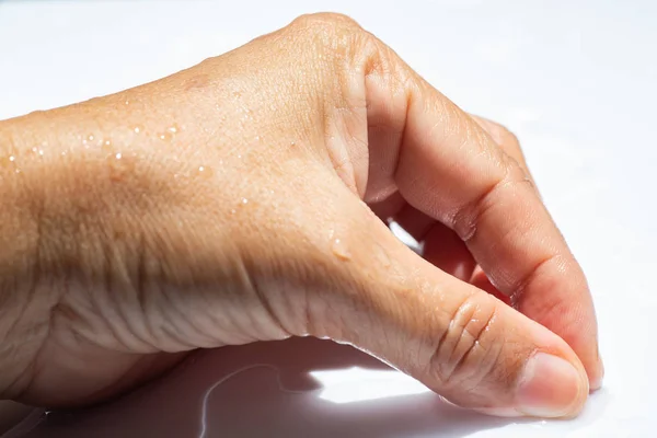 Женская влажная боковая рука с капельками воды на белом акриловом фоне, Крупный план и макроснимок, Выборочный фокус, часть азиатской кожи тела, расслабляющая ванна, концепция здравоохранения — стоковое фото