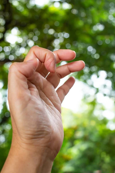 Trigger Finger lock on thumb and index finger of woman's side left hand, Suffering from pain, in bokeh green garden background, Close up & Macr