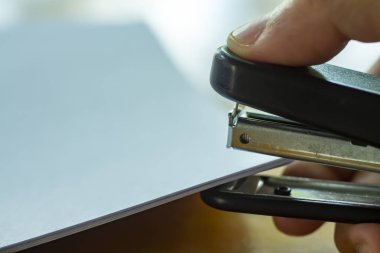 Kadın sağ el zımba tutarak ve ahşap arka planda beyaz kağıt zımbalama, yakın yukarı & makro Shot, seçici odak, Office Kırtasiye kavramı