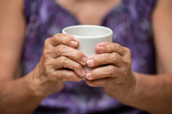Senior vrouw handen houden kopje aromatische thee in bokeh paarse kleren achtergrond, Aziatische lichaam huid deel, ontspannen tijd & drank concept — Stockfoto