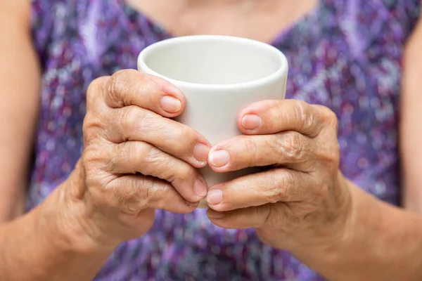 Senior vrouw handen houden kopje aromatische thee in bokeh paarse kleren achtergrond, Aziatische lichaam huid deel, ontspannen tijd & drank concept — Stockfoto