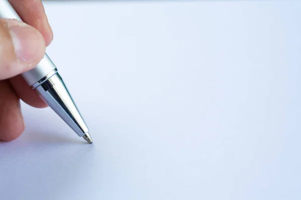 Woman's left Hand holding a silver pen, writing letter on white paper background, Notebook, Close up & Macro shot, Selective focus, Communication, Stationery concept