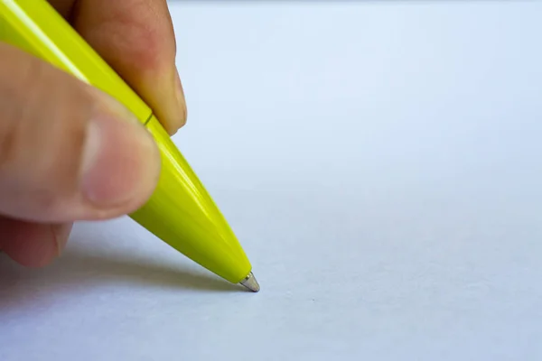 Woman's left Hand holding a green pen, writing letter on white paper background, Notebook, Close up & Macro shot, Selective focus, Communication, Stationery concept