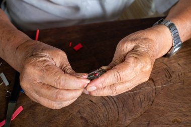 Kıdemli adam ' s elleri muska sağlamak için, ahşap masa dokusu arka planda bir metal kap ile küçük Buddha görüntü, yakın çekim & makro Shot, Asya vücut parçası, craftman işleme kavramı