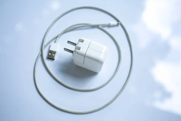 Τροφοδοτικό USB για συσκευές, καλώδιο φορτιστής σε λευκό ακρυλικό φόντο τραπεζιού, κοντινό πλάνο και στιγμιότυπο, επιλεκτική εστίαση, τεχνολογία, επιχειρηματική έννοια — Φωτογραφία Αρχείου